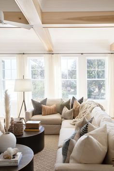 a living room filled with lots of furniture next to two large windows and a coffee table