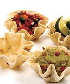 four tortilla cups filled with guacamole and salsa