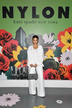 a woman standing in front of a wall with flowers and the words nylon on it