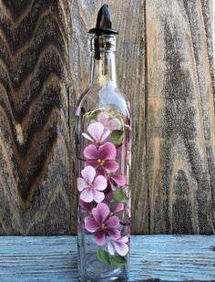 a glass bottle filled with flowers on top of a wooden table