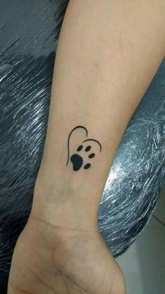 a dog paw and heart tattoo on the left wrist, with a black outline in the middle