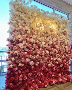 a wall made out of flowers with the words let's party written on it