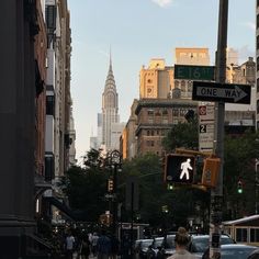 people are walking down the street in front of tall buildings