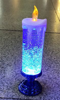 a lit candle sitting on top of a blue table next to a tiled floor and wall