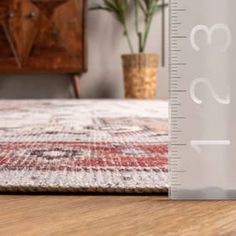 a ruler is on the floor next to a potted plant and a wooden dresser