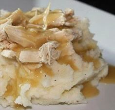 a white plate topped with mashed potatoes covered in gravy