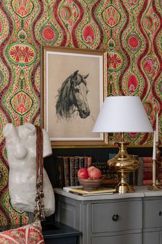 a horse head is on the wall next to a lamp and some books in front of it