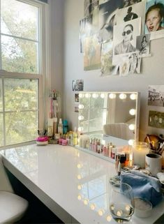 a vanity with lights on it in front of a large window and pictures above the mirror