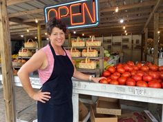 a woman standing in front of a display of tomatoes