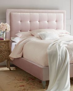 a pink bed with white sheets and pillows on top of it next to a night stand