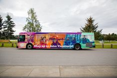 a brightly colored bus is parked on the side of the road in front of some trees