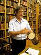 a man standing in front of a bookshelf holding two drum's and looking at the camera