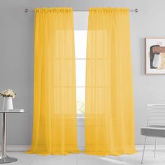 a yellow curtain hanging on the side of a wall next to a chair and table