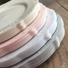 a stack of white and pink plates sitting on top of a wooden table