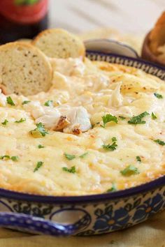 a blue and white bowl filled with food next to bread