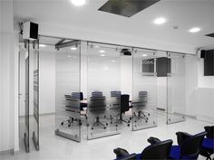 an empty conference room with blue chairs and glass partitions to divide the space from the rest of the room