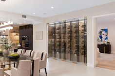 a dining room table with chairs and a vase on top of it in front of a wine rack