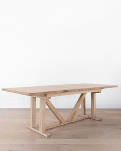 a wooden table sitting on top of a hard wood floor next to a white wall