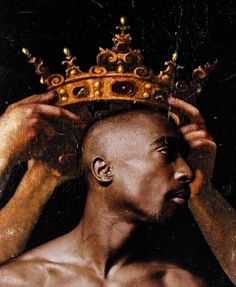 a man with a crown on his head is looking at the camera while holding it over his head