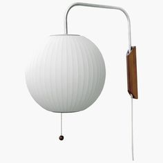 a white ball hanging from the side of a wall light with a wooden arm and metal frame