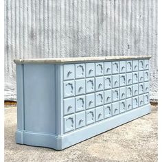 a large blue cabinet with drawers on the top and bottom, sitting in front of a wall