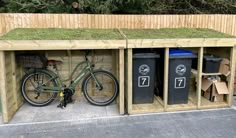 a bike is parked in front of a shed with grass on the roof and trash cans