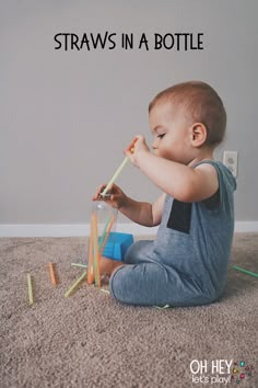 a baby sitting on the floor playing with crayons and building blocks in front of him