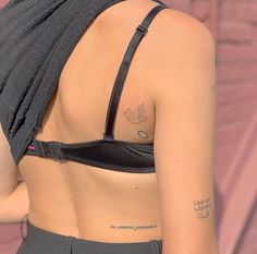 the back of a woman's bra with tattoos on her left arm and chest