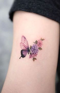 a small butterfly with pink flowers on the side of her leg and it's wings spread