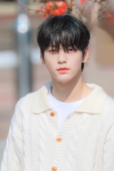 a young man with black hair wearing a white sweater