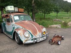 an old car with luggage on top is parked next to a trailer and other items