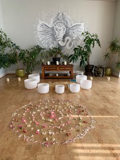 the room is decorated with white candles and pink flowers on the floor, surrounded by potted plants