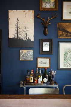 there are many framed pictures on the wall above the bar area in this room, including deer heads