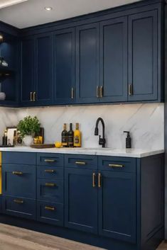 a kitchen with blue cabinets and marble counter tops, gold pulls on the handles is shown