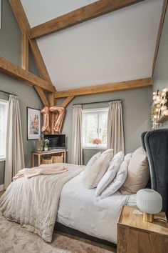 a large bed sitting in a bedroom next to two windows and a wooden frame on the wall