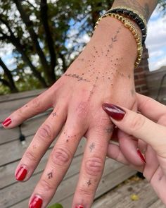 two people with red fingernails and tattoos on their hands are holding each other's hand