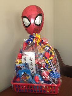 a spiderman balloon and some toys in a basket