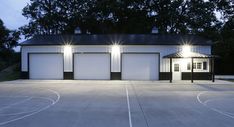 an empty basketball court at night with lights shining on the building and trees in the background