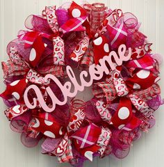 a red and pink wreath with the word welcome on it