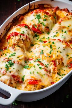 a casserole dish with chicken and cheese covered in parmesan sauce, garnished with green herbs