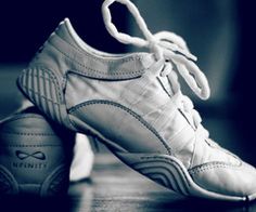 a pair of white tennis shoes sitting on top of a wooden table next to a black and white photo