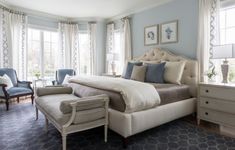 a large bedroom with blue walls and white furniture in the corner, along with two chairs