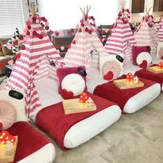 a room filled with lots of red and white beds covered in paper tents next to each other