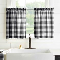 a black and white checkered window curtain hanging in front of a sink with a faucet