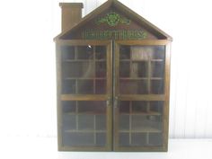 a wooden book case with glass doors on the front and bottom shelves in green lettering