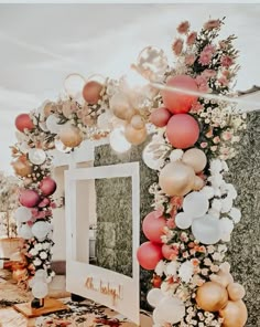 a table topped with balloons and flowers next to a white framed photo frame filled with confetti