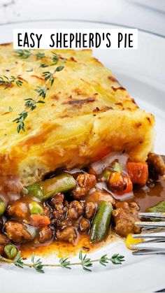 a white plate topped with shepherd's pie covered in gravy and vegetables