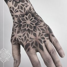 a person's hand with black and white tattoos on it, showing the intricate design