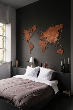 a bed in a bedroom with a large wooden world map on the wall above it