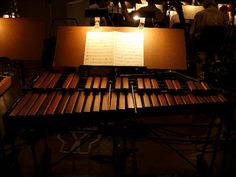 a musical instrument with sheet music on it and people in the background playing instruments behind them